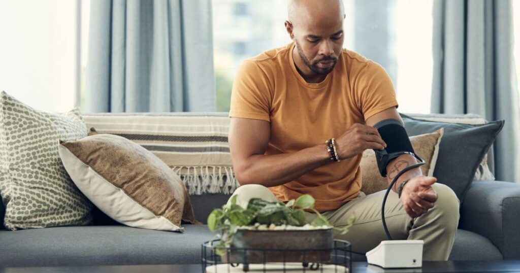 man on couch checking blood pressure from home