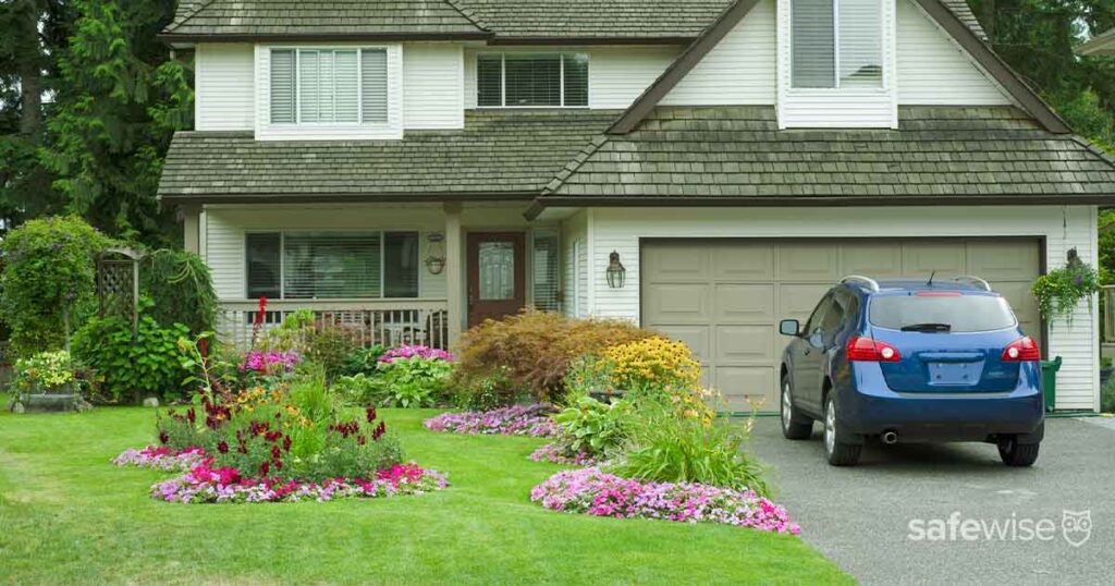 blue car parked in driveway of well manicured white house