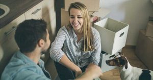 couple sitting on floor with moving boxes and a dog