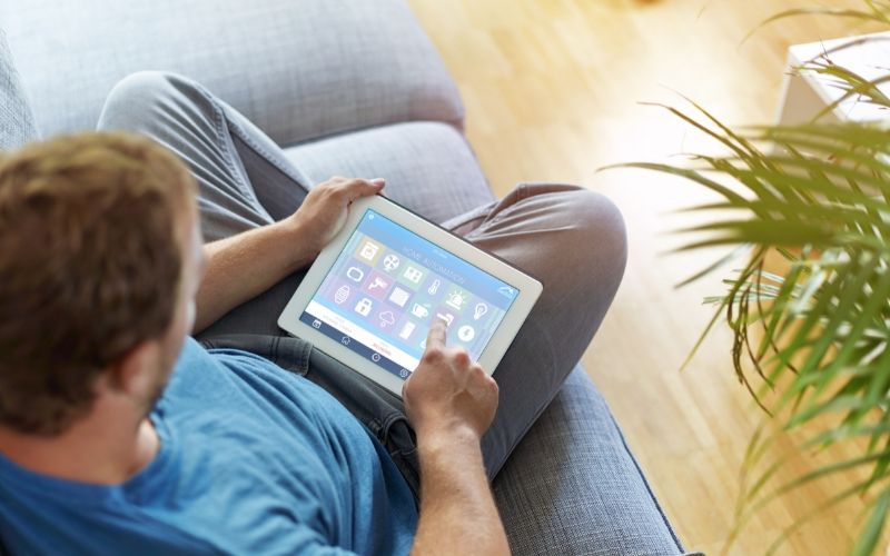 man on couch looking at security system options on a tablet