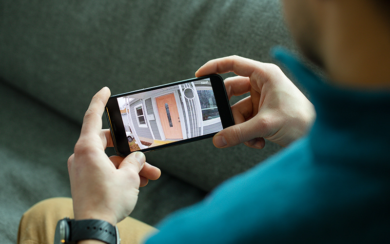 hands holding a smartphone with footage from a security camera