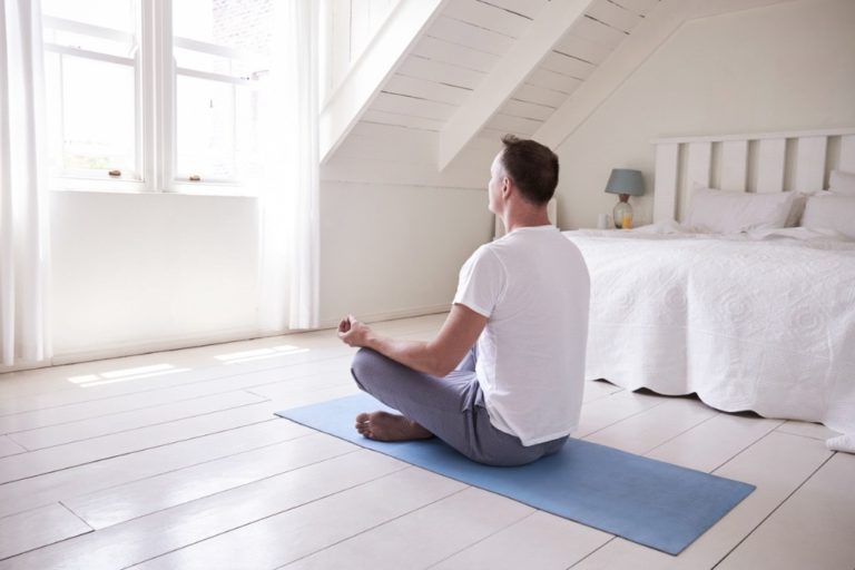 man meditating in bedroom