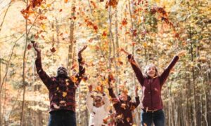 family throwing leaves up in the woods