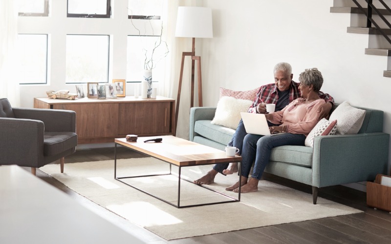 older couple sitting on couch with computer