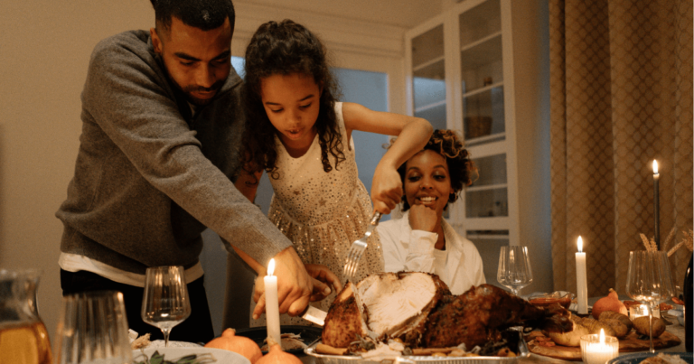 family at Thanksgiving carving turkey